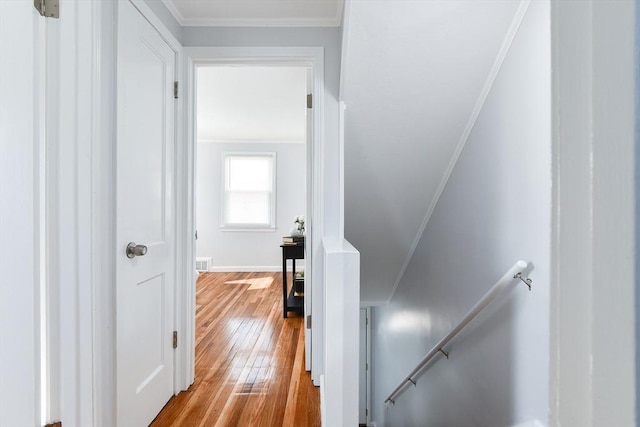 hall with visible vents, an upstairs landing, hardwood / wood-style flooring, crown molding, and baseboards