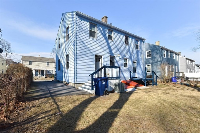 back of property featuring cooling unit, a yard, a chimney, and fence