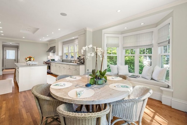 dining room with light wood-type flooring, crown molding, and recessed lighting