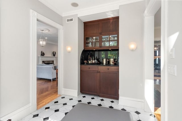 indoor bar with crown molding, a fireplace, and baseboards