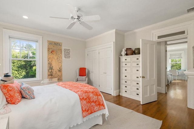 bedroom featuring dark wood-style flooring, crown molding, a closet, ceiling fan, and baseboards