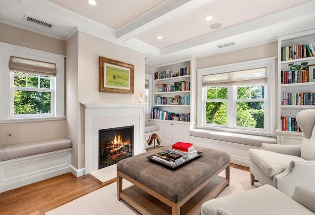 sitting room with wood finished floors, a fireplace with flush hearth, ornamental molding, and recessed lighting