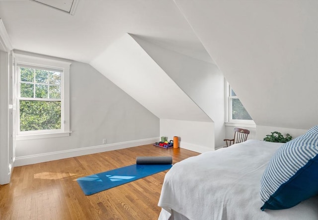 bedroom with lofted ceiling, wood finished floors, and baseboards