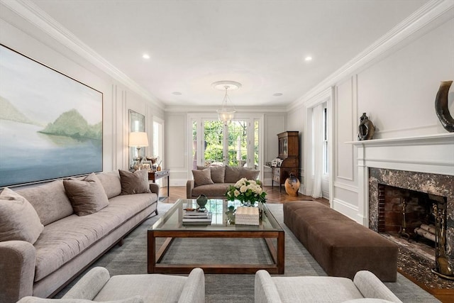 living room featuring ornamental molding, a premium fireplace, a decorative wall, recessed lighting, and wood finished floors