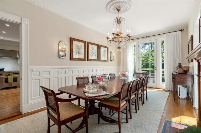 dining room featuring a chandelier, crown molding, wood finished floors, a wainscoted wall, and recessed lighting