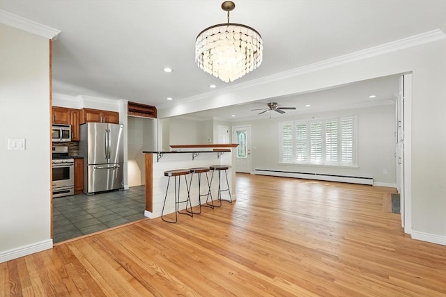 15 Oak Bluff Cir, East Longmeadow, MA 01028 - kitchen featuring appliances with stainless steel finishes, baseboard heating, crown molding, light wood-style floors, and a breakfast bar