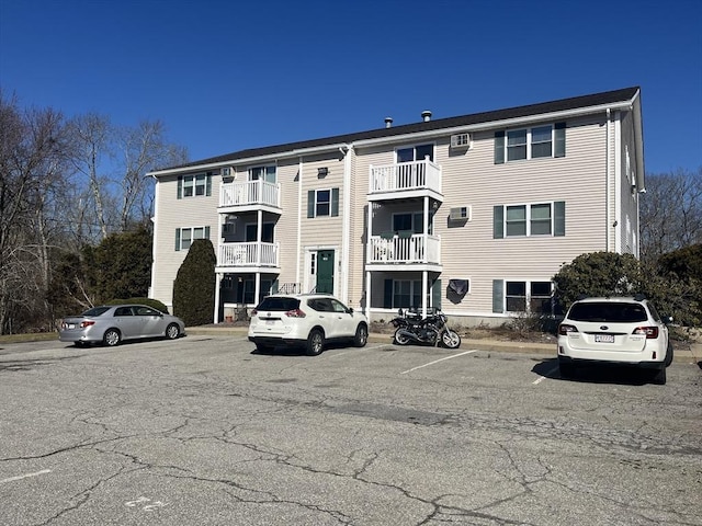 view of property featuring uncovered parking and a wall mounted AC