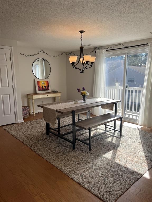 dining area featuring a textured ceiling, a chandelier, and wood finished floors