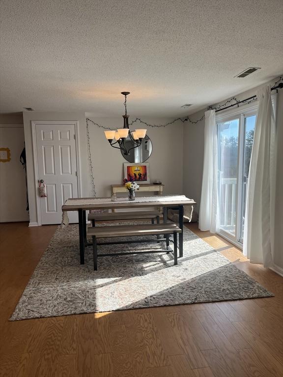 dining room featuring a chandelier, a textured ceiling, and wood finished floors