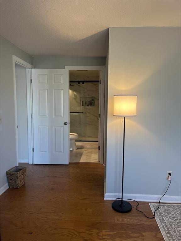 hall featuring baseboards, dark wood-style floors, and a textured ceiling