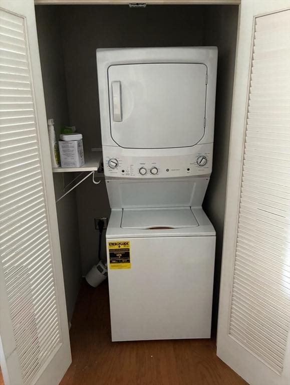 laundry room with stacked washer / drying machine and wood finished floors