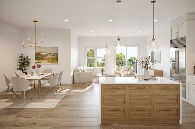 kitchen with white cabinets, pendant lighting, a chandelier, built in fridge, and light wood-type flooring