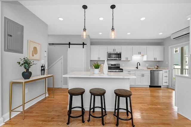 kitchen with appliances with stainless steel finishes, a barn door, light hardwood / wood-style flooring, and electric panel