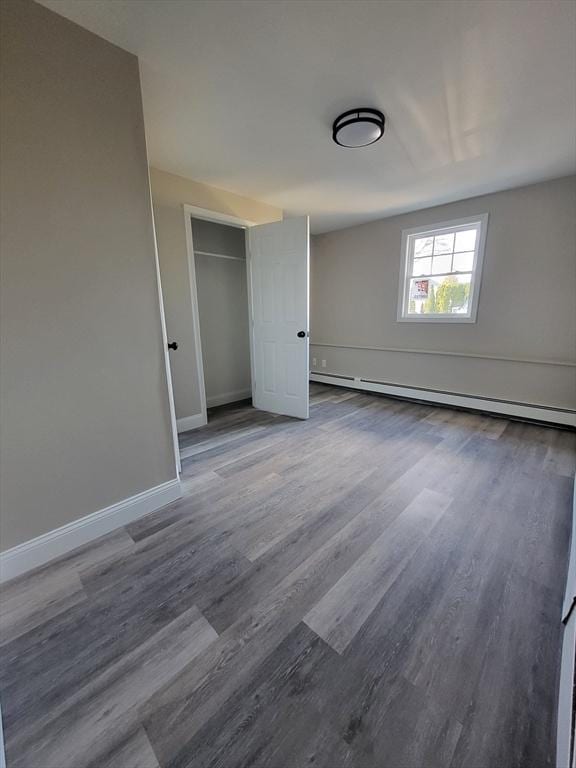 unfurnished bedroom with dark hardwood / wood-style floors, a closet, and a baseboard radiator