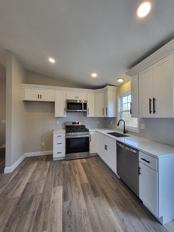 kitchen featuring white cabinetry, sink, dark wood-type flooring, vaulted ceiling, and appliances with stainless steel finishes