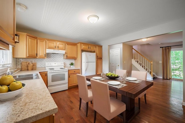 kitchen with white appliances, under cabinet range hood, a sink, and light countertops