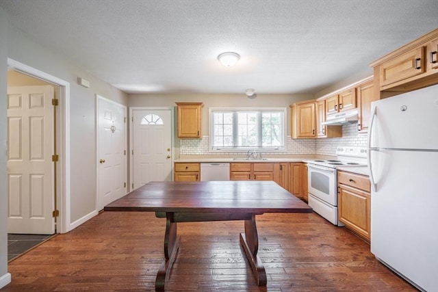 kitchen featuring white appliances, under cabinet range hood, light brown cabinets, a sink, and a textured ceiling