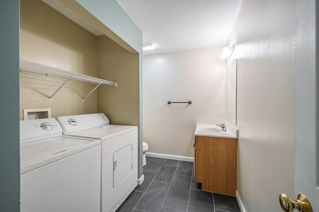 laundry area featuring washing machine and clothes dryer, baseboards, and dark tile patterned floors