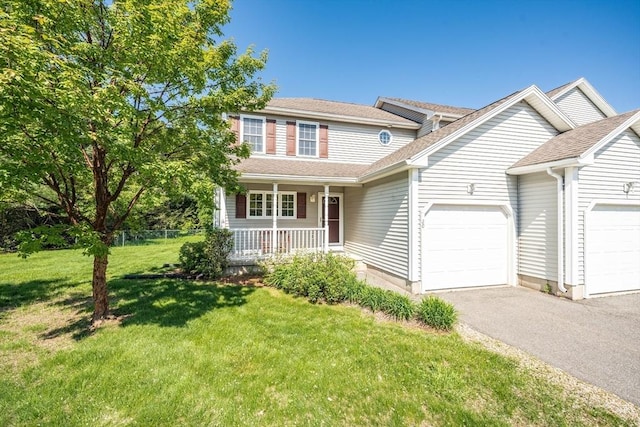 traditional-style home with a garage, covered porch, asphalt driveway, a front yard, and roof with shingles