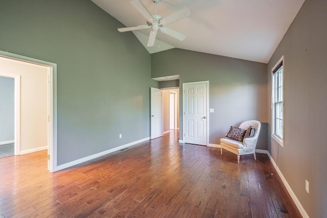 living area with ceiling fan, wood finished floors, baseboards, and high vaulted ceiling