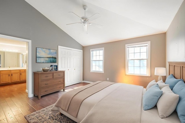 bedroom featuring light wood-type flooring, a closet, high vaulted ceiling, ensuite bath, and ceiling fan