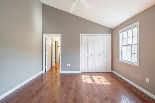 unfurnished bedroom with lofted ceiling, dark wood-style flooring, baseboards, a closet, and ceiling fan