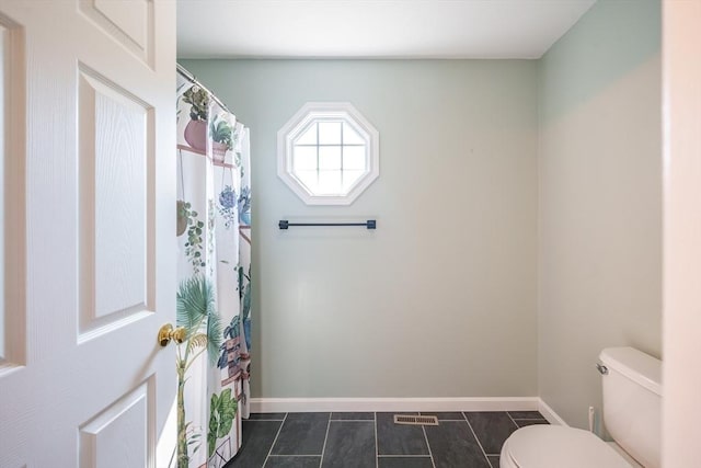 bathroom with toilet, baseboards, and tile patterned floors