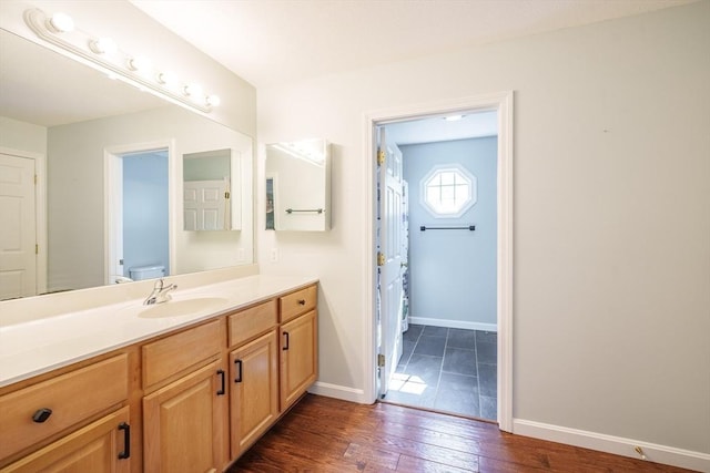 bathroom featuring wood finished floors, baseboards, toilet, and vanity