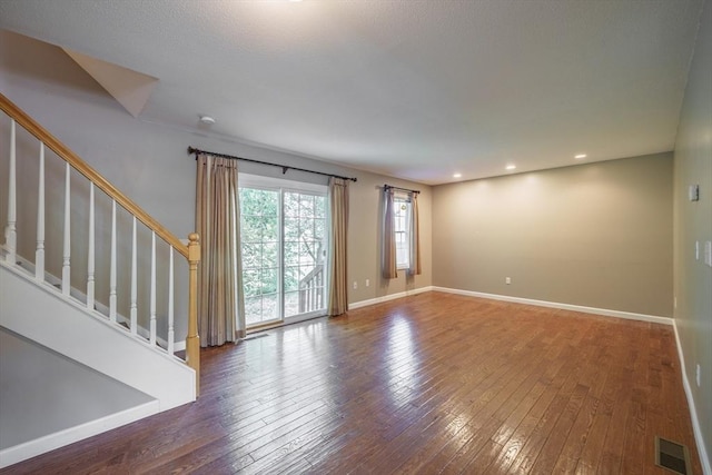unfurnished living room with wood-type flooring, stairway, baseboards, and recessed lighting