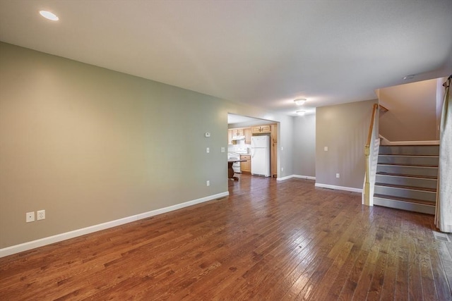 unfurnished living room with dark wood finished floors, stairs, baseboards, and recessed lighting