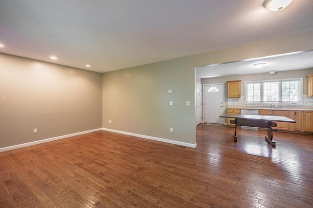 unfurnished living room featuring dark wood-style floors, baseboards, recessed lighting, and a sink