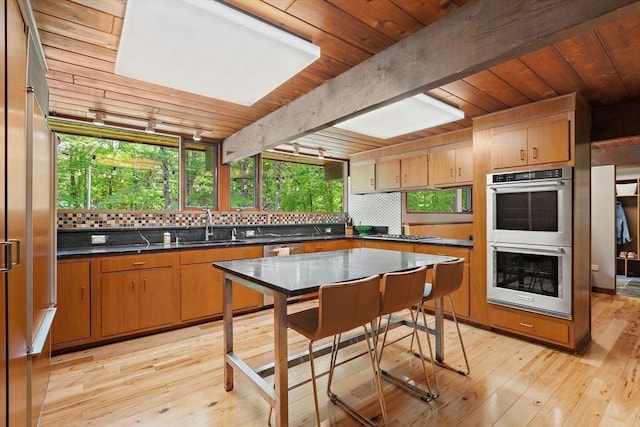 183 Indian Hl, Carlisle, MA 01741 - kitchen with appliances with stainless steel finishes, wooden ceiling with exposed beams, dark countertops, tasteful backsplash, and light wood-style flooring