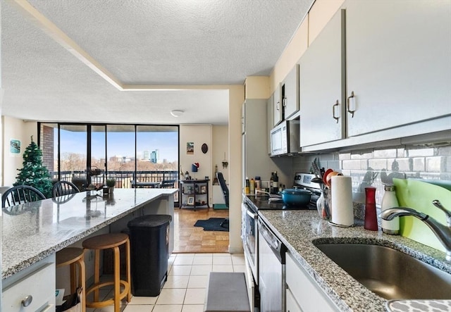 kitchen featuring light tile patterned floors, white cabinetry, stainless steel appliances, a breakfast bar, and sink