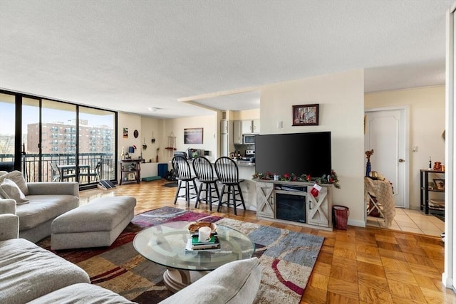 living room with a textured ceiling, light parquet floors, and a wall of windows