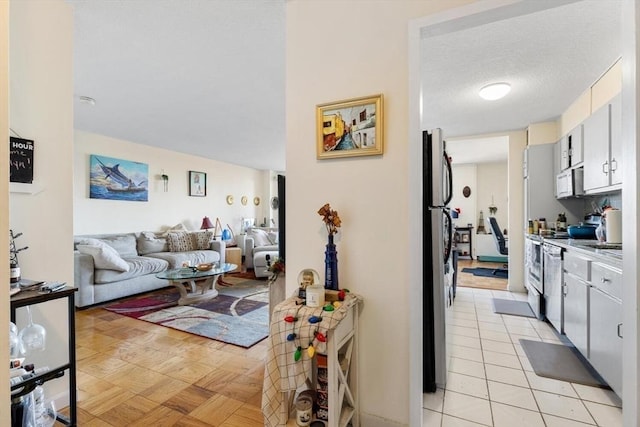 interior space featuring light parquet flooring, white cabinetry, appliances with stainless steel finishes, and a textured ceiling