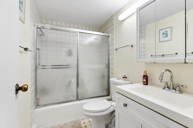 full bathroom featuring combined bath / shower with glass door, vanity, and toilet