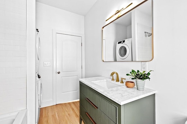 bathroom with washtub / shower combination, wood finished floors, and vanity