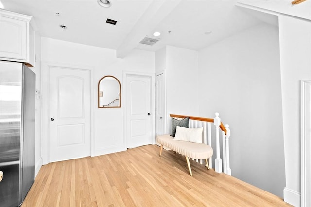 living area with light wood finished floors, recessed lighting, visible vents, and an upstairs landing