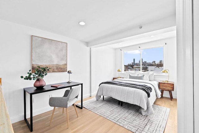 bedroom with a view of city, baseboards, wood finished floors, and recessed lighting