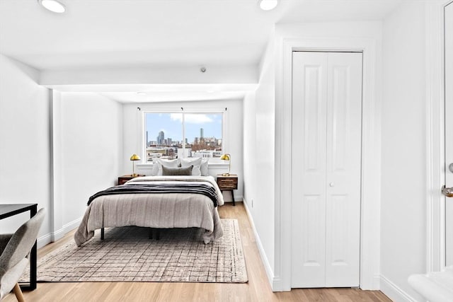 bedroom with a closet, recessed lighting, light wood-style flooring, and baseboards