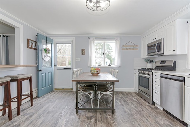 197 N St, Mattapoisett, MA 02739 - kitchen with stainless steel appliances, white cabinets, light wood-type flooring, light countertops, and ornamental molding