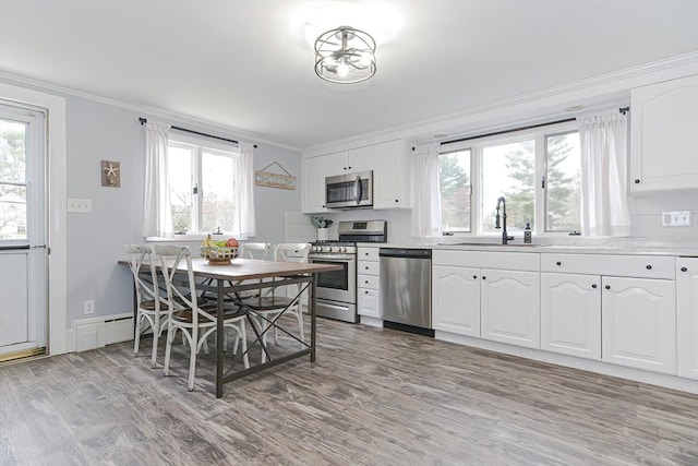197 N St, Mattapoisett, MA 02739 - kitchen with stainless steel appliances, a sink, crown molding, light wood-type flooring, and white cabinetry