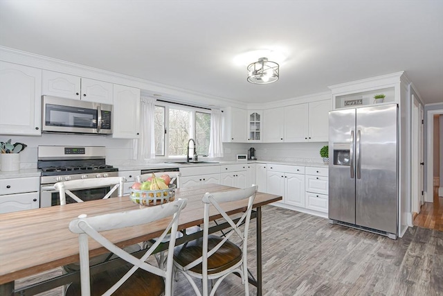 197 N St, Mattapoisett, MA 02739 - kitchen with appliances with stainless steel finishes, a sink, light countertops, white cabinetry, and light wood-type flooring