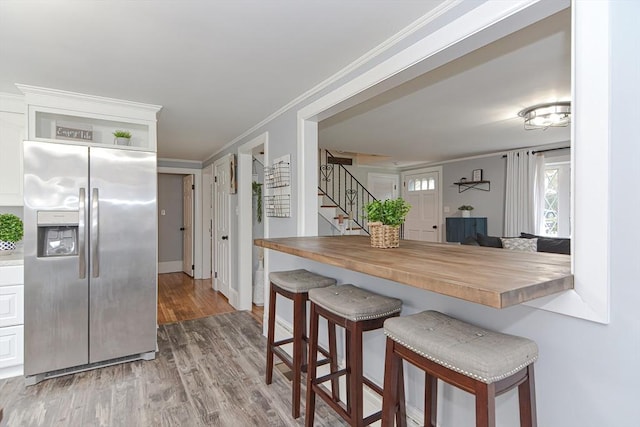 197 N St, Mattapoisett, MA 02739 - kitchen with stainless steel fridge with ice dispenser, butcher block counters, a kitchen bar, wood finished floors, and crown molding