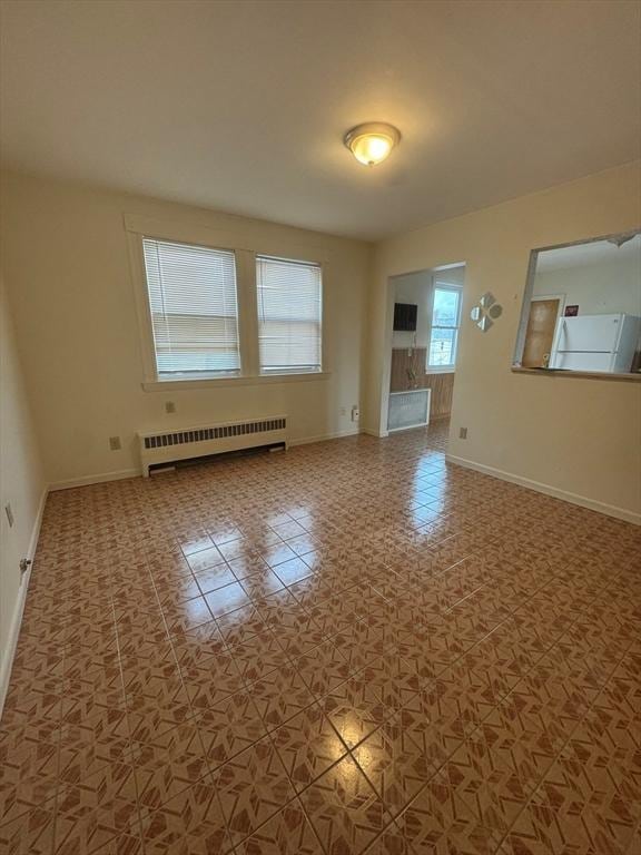 unfurnished room with tile patterned flooring, radiator, and baseboards