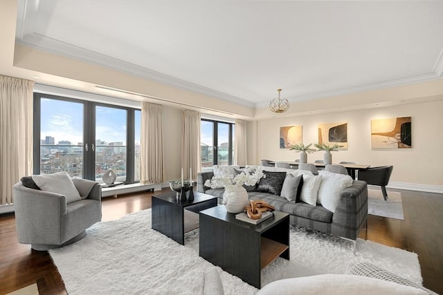 living room with wood finished floors, a raised ceiling, baseboards, and ornamental molding