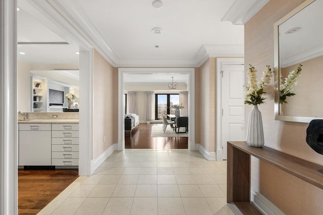 corridor with a sink, baseboards, light tile patterned flooring, and crown molding