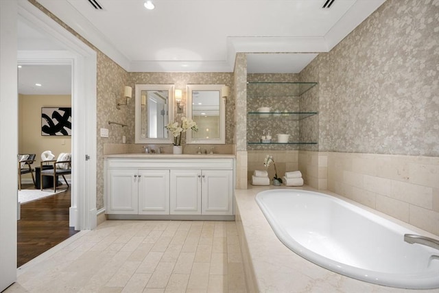 bathroom featuring double vanity, wallpapered walls, a garden tub, and a sink