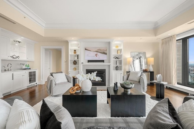 living room featuring a wealth of natural light, a glass covered fireplace, bar, and crown molding