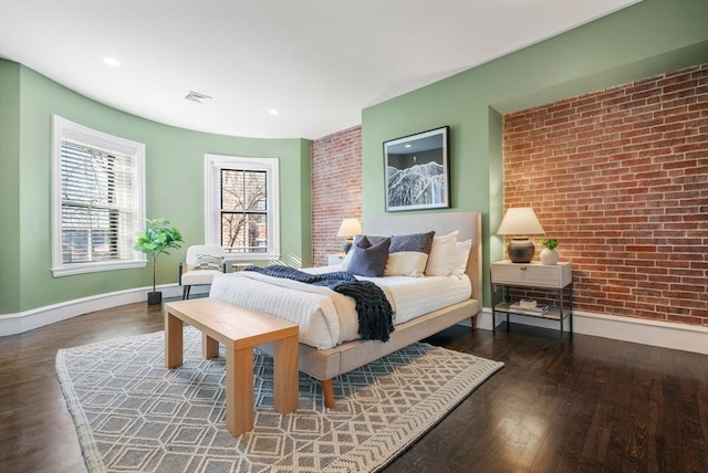 bedroom with brick wall and dark wood-type flooring